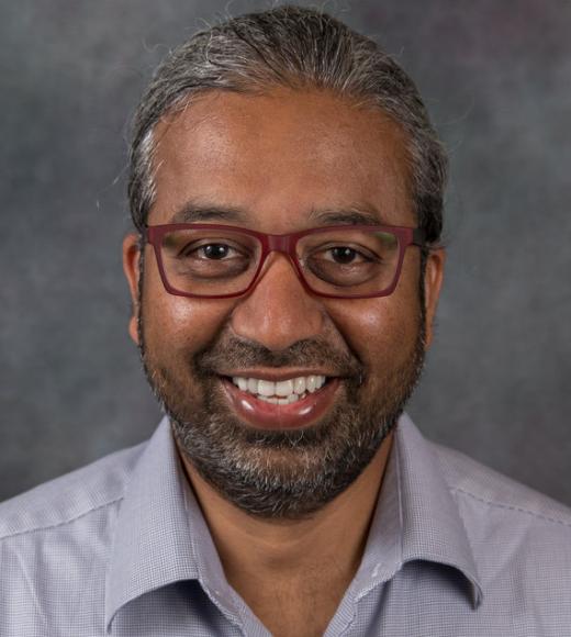 Middle aged South Asian man's headshot. He has eyeglasses and a polo shirt.