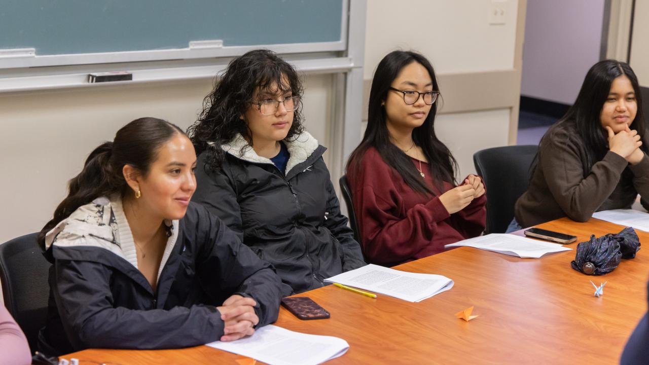 Four students gather around a table in conversation