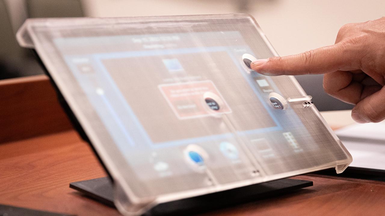 A plastic overlay with holes cut out sits on top of a computer screen