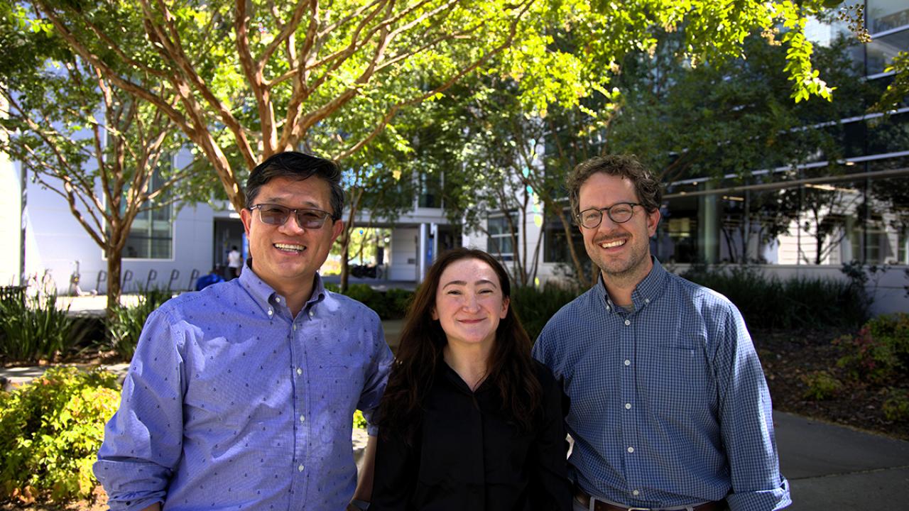 Three people stand outdoors