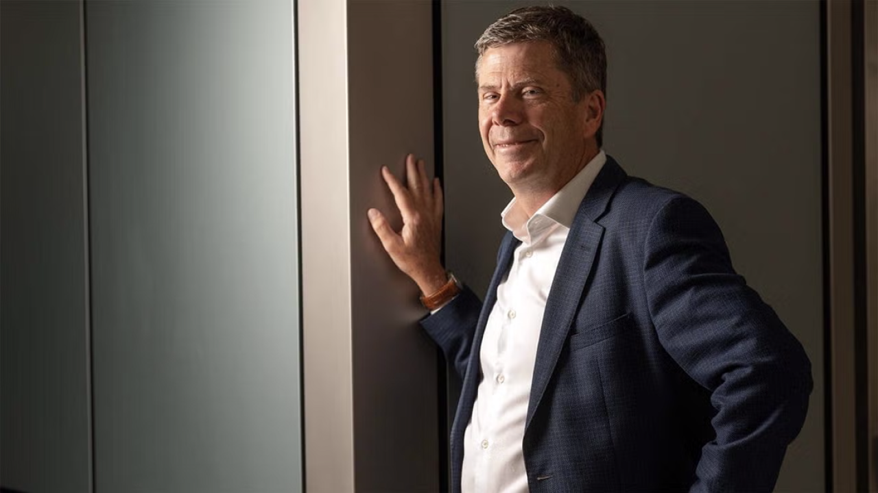 Simon Cherry wears a suit and stands with one hand against the wall