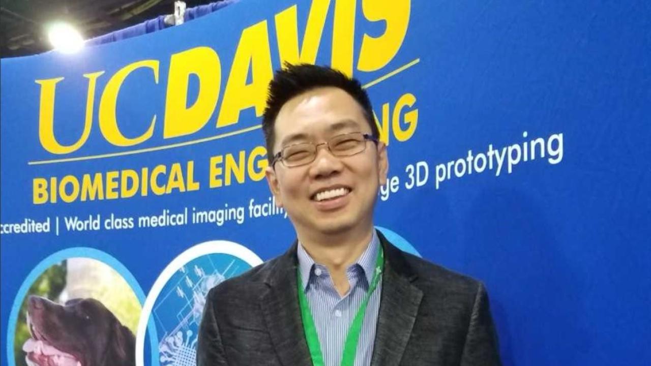 Dr. Cheemeng Tan standing in front of a display for UCD's BME department