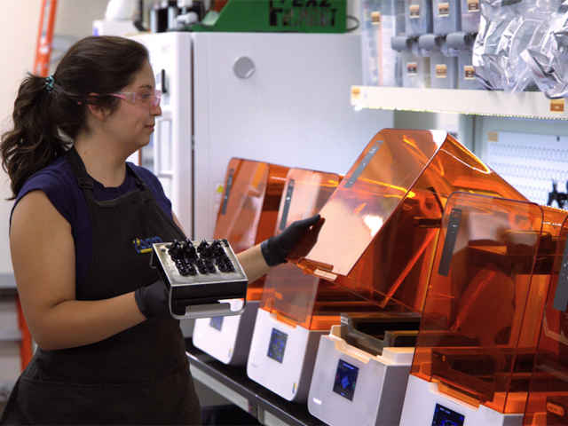 Valerie Quiroz with orange 3D printers