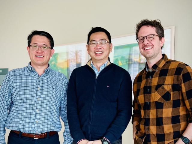 Three people standing together for a group photo indoors