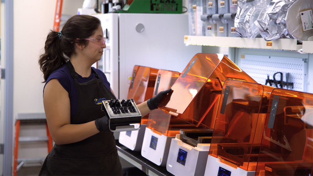 Valerie Quiroz with orange 3D printers