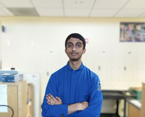 Young South Asian man in a blue lab coat inside a laboratory