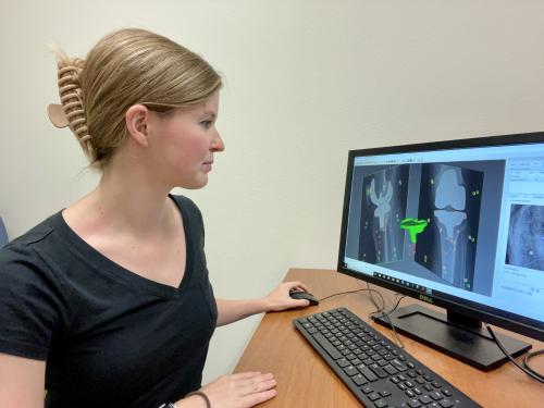 UC Davis grad student Abby Niesen sits at a desk with computer screen showing 3D imaging