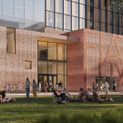 Many students lounging on a lawn in front of an architectural rendering of Aggie Square's east entrance