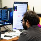 Person sits at a computer with three monitors