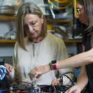 Three people in a lab with gloves on touching different color cables